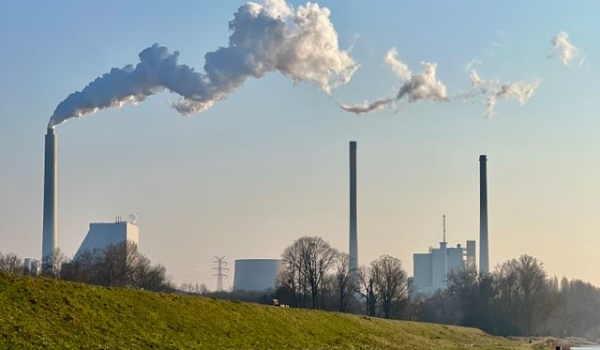 Industrial chimneys with smoke emissions under a clear blue sky